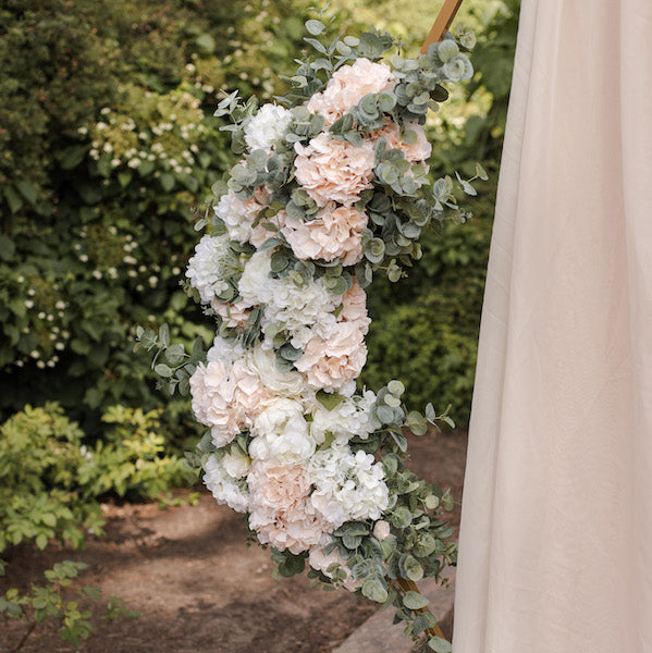 Iso silkkikukka-asetelma kiinnitettynä vihkikaareen.