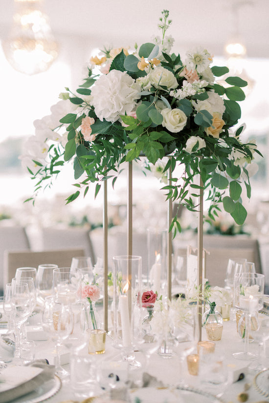Valkoisilla ja persikan värisillä kukilla koristeltu hääjuhlan pöytä